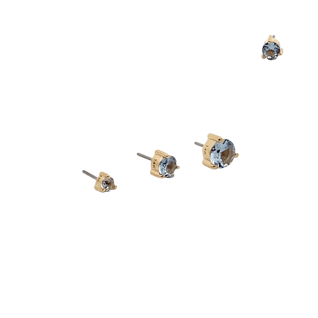 Set of gold aquamarine stud earrings with gemstones on a black background