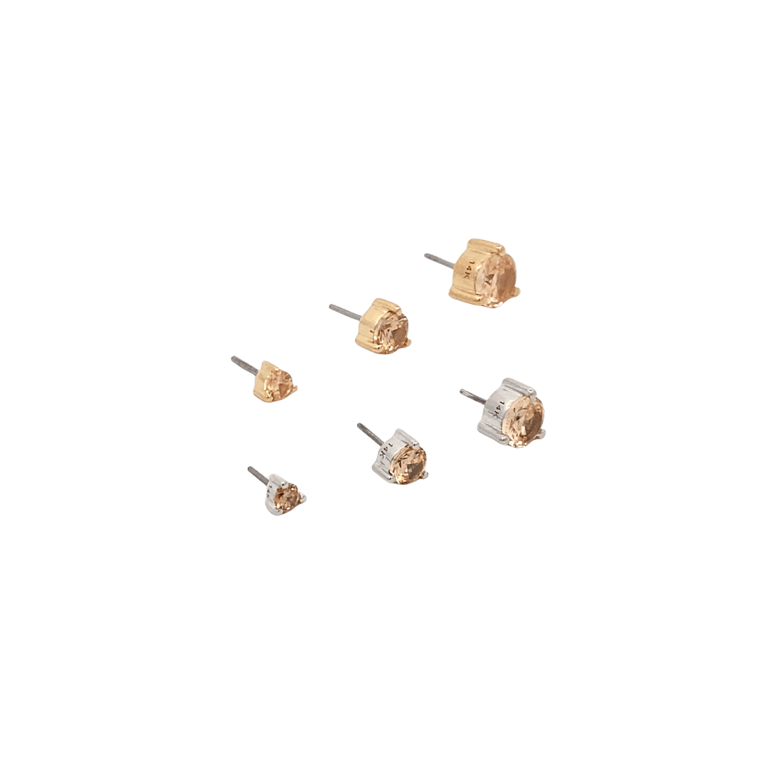 Set of small gold and silver stud earrings on a black background